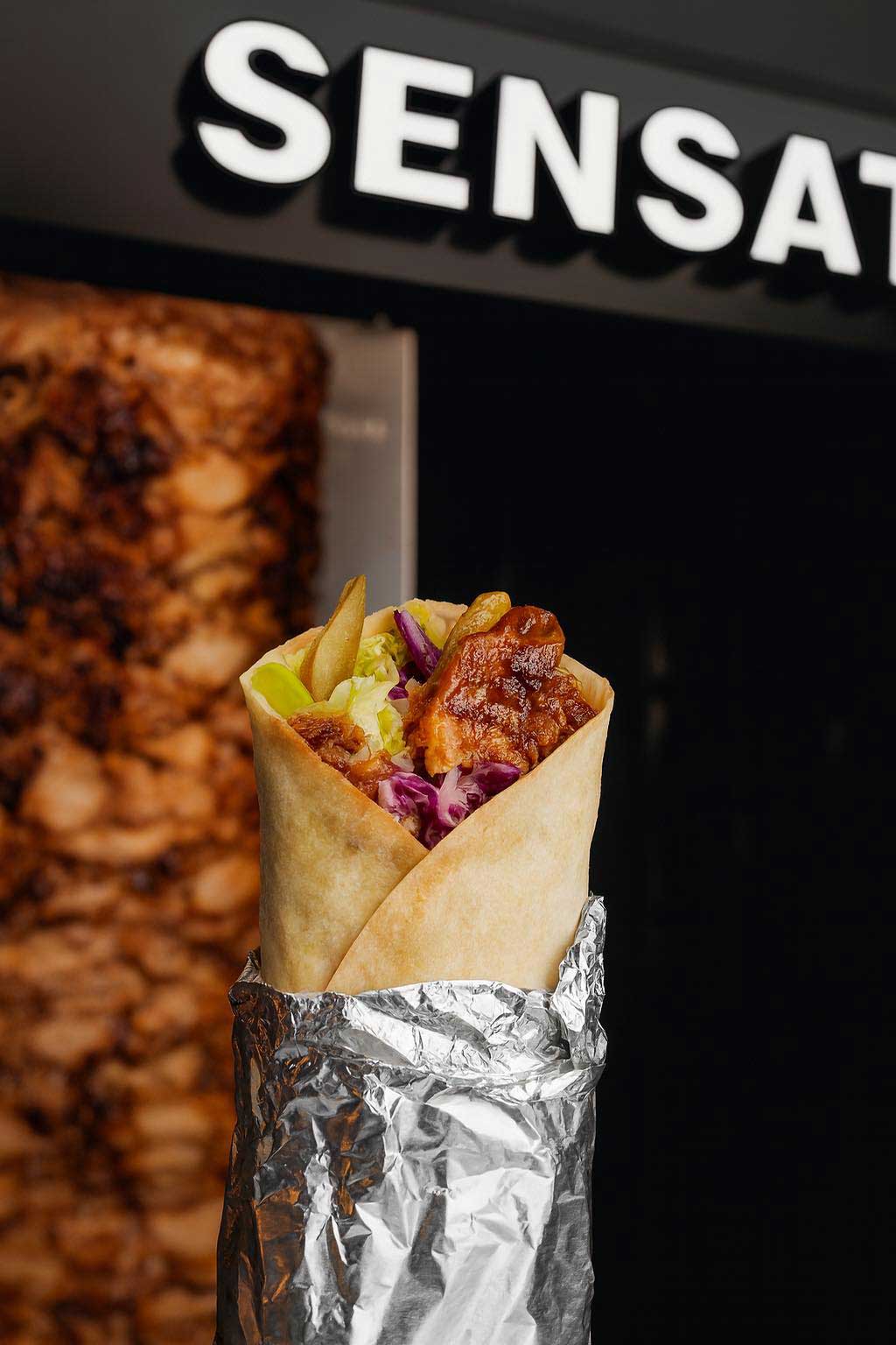 Sensation Takeaway doner wraps with meat, cabbage, and fries, wrapped in foil.